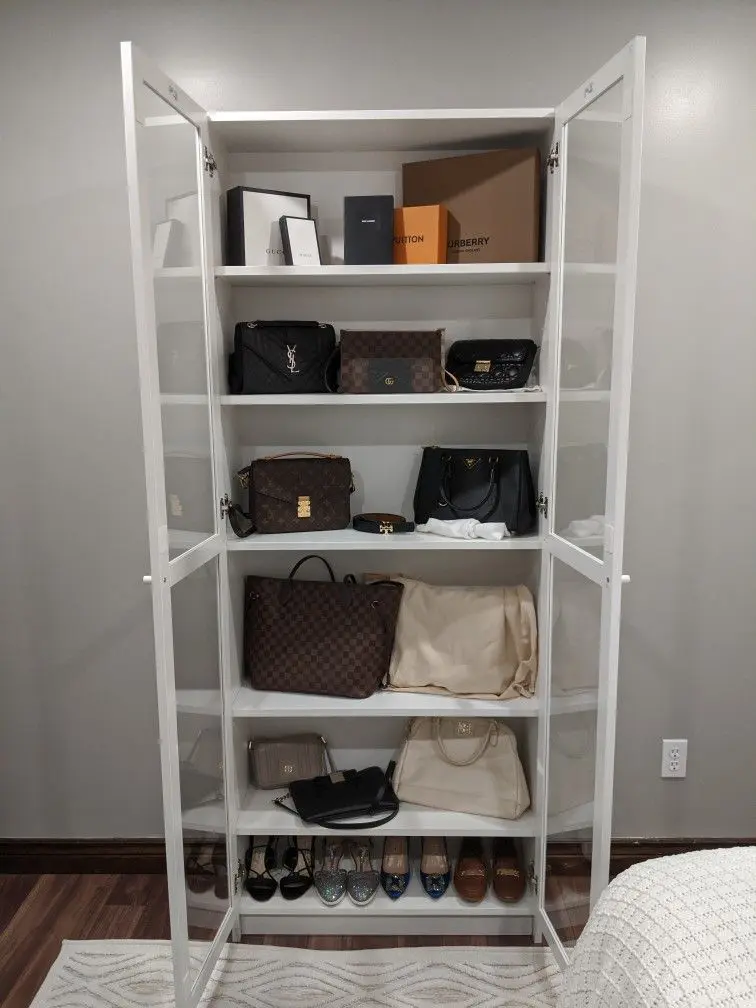 Minimalist white open wardrobe with shelves displaying handbags, shoes, and storage boxes.