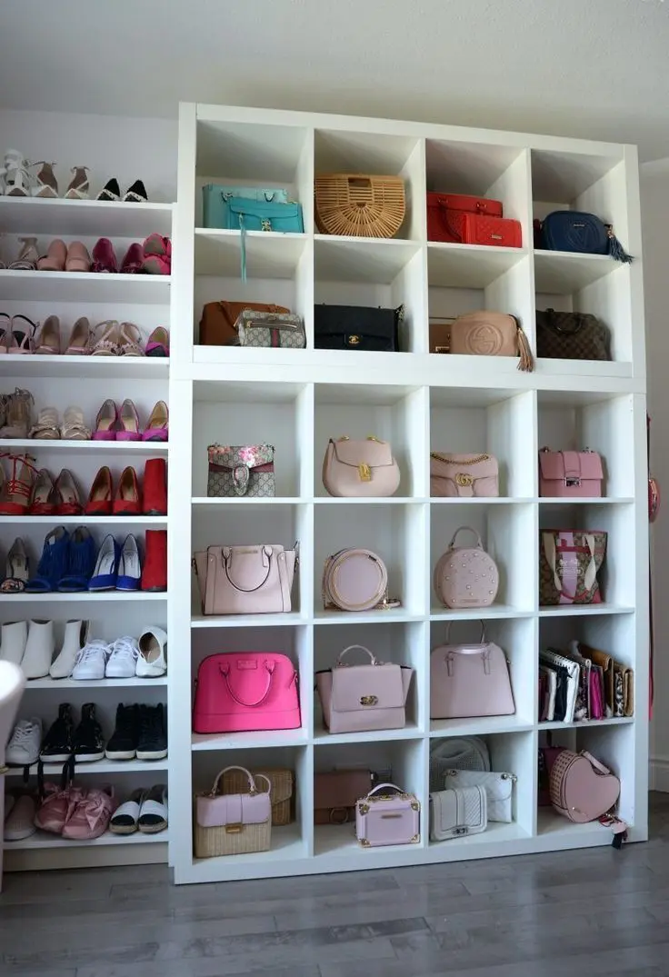 Large white cubby shelving unit with one handbag per cubby, some paired with shoes.