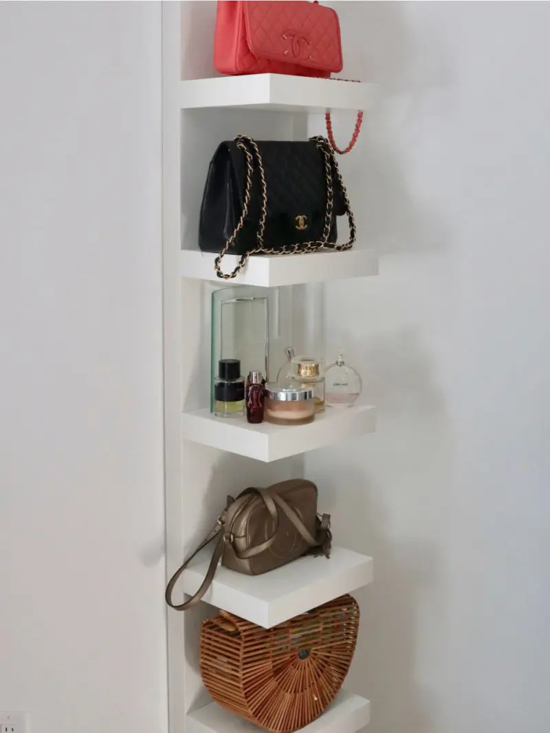 L shaped corner floating shelves holding handbags, perfumes, and a woven bag.