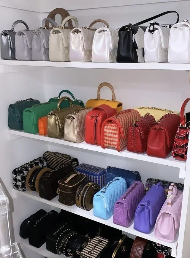 Handbags organized by color on white shelves creating a rainbow display.