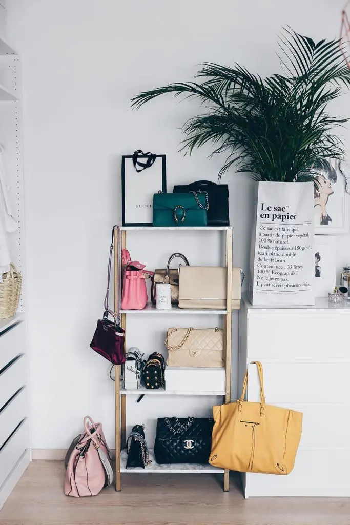 Freestanding shelf with handbags and a green potted plant on top creating a warm, inviting display.