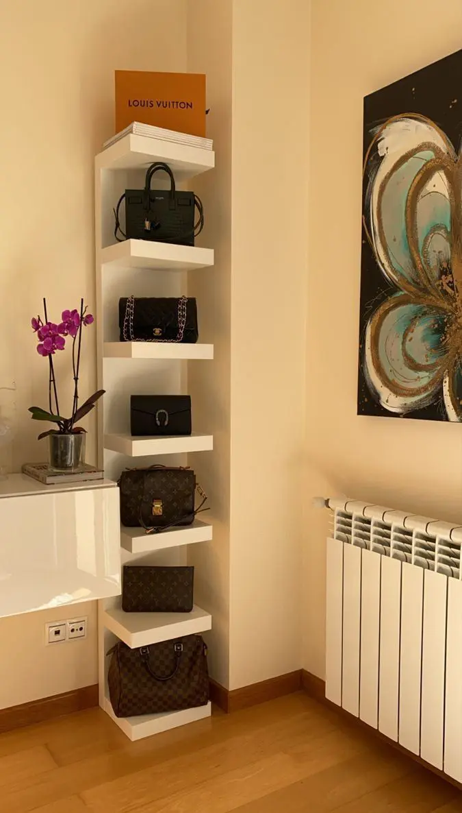 Vertical stack of floating shelves displaying handbags in a narrow wall space.