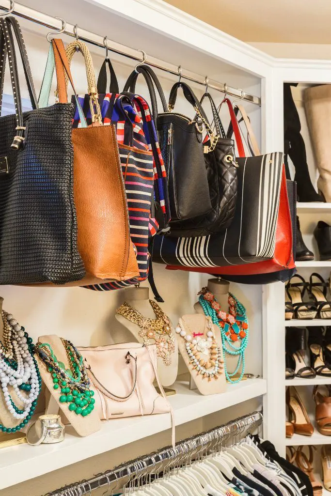 Closet shelf with handbags and statement necklaces on display busts creating a styling station.