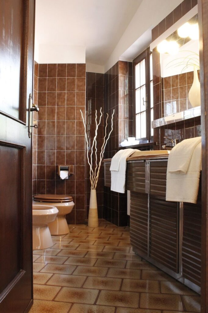 Vintage bathroom with clawfoot tub, patterned wallpaper, and warm brown finishes