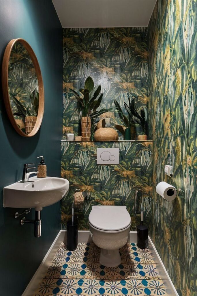 Lush botanical wallpaper with green leaves and light florals in a compact bathroom.