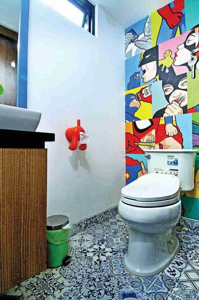 Colorful abstract wallpaper with bold strokes and shapes creating an energetic focal wall in a small bathroom.