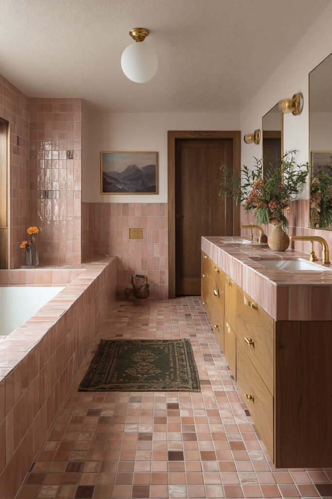 Bathroom with mauve geometric wall tiles, matching floor tones, glass shower, and a round mirror.
