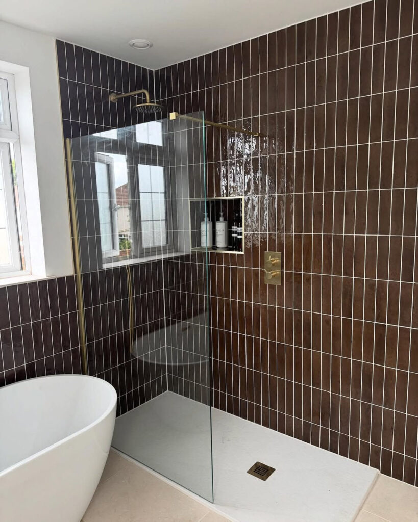 Bathroom with glossy chocolate brown tiles and a white freestanding tub