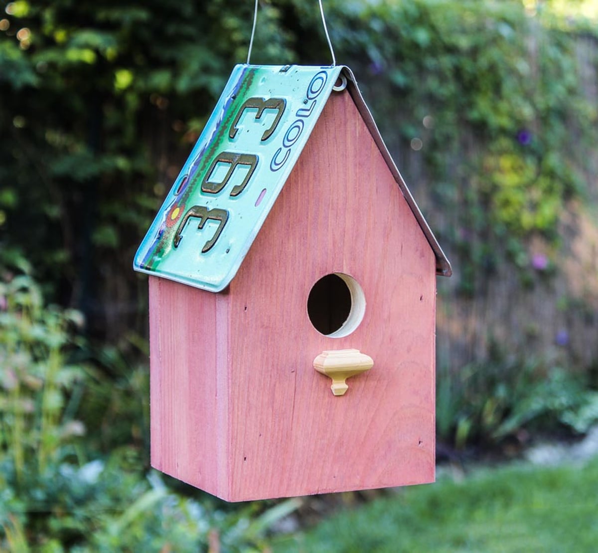 The Pink License Plate Cabin birdhouse painted dusty rose with a metal license plate roof.