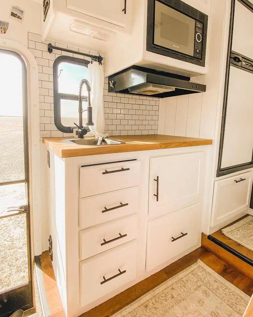 Clean white RV kitchen with wood countertops
