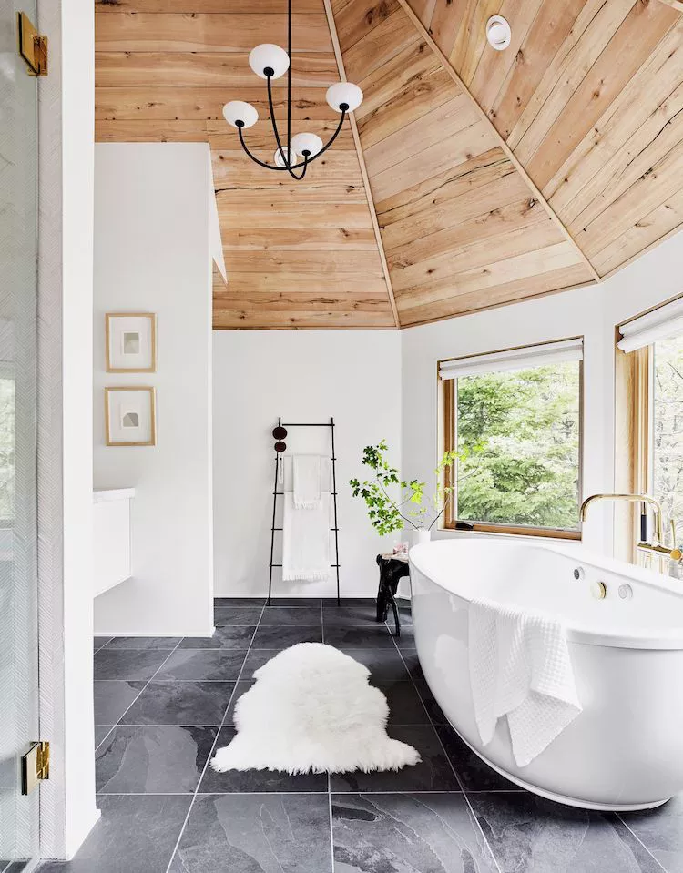 Shared bathroom with a double-wide white trough sink, two faucets, black hardware, and a simple wood shelf.