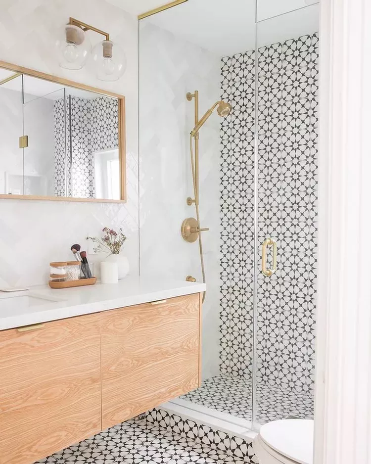 Industrial bathroom with exposed brick walls, black-framed glass shower doors, and a simple wood vanity with integrated white sink.