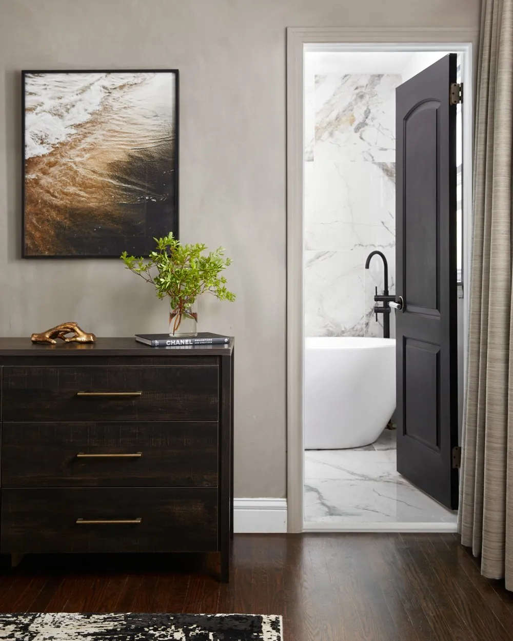 Vibrant bathroom with terracotta tiles on the floor and an accent wall, white pedestal sink, and round wood-framed mirror.