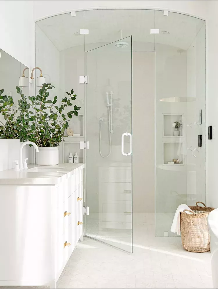 Coastal bathroom with dusty blue shiplap walls, white vanity, silver hardware, woven seagrass basket, and a white-framed mirror.