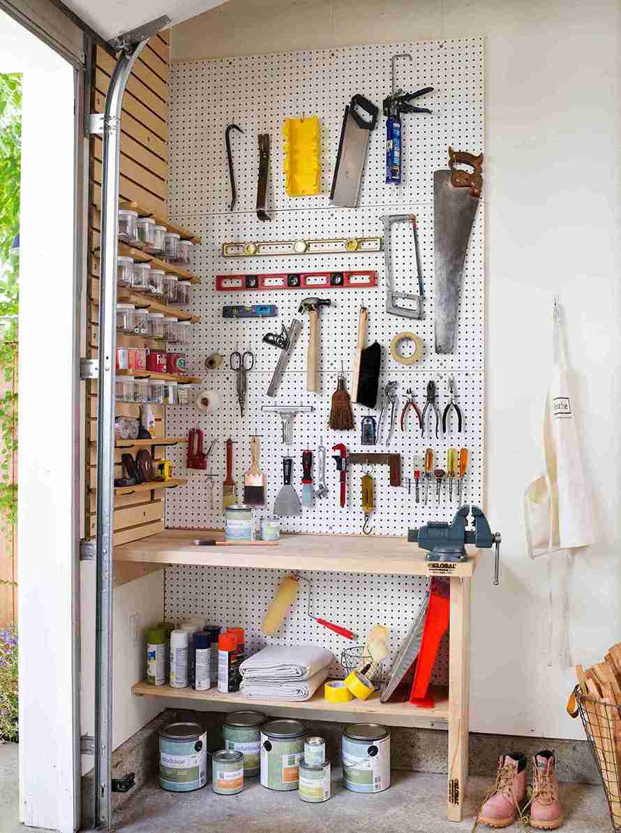 Floor to ceiling pegboard wall with tools organized above wooden workbench