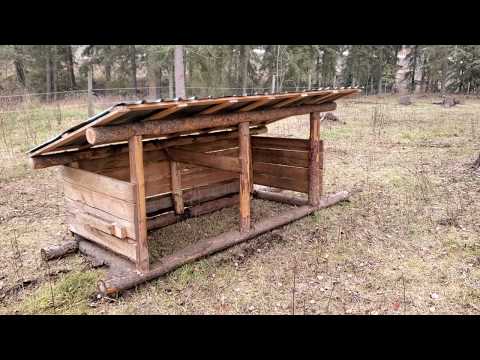 Rustic log cabin style goat shelter with thick timber supports and slanted roof