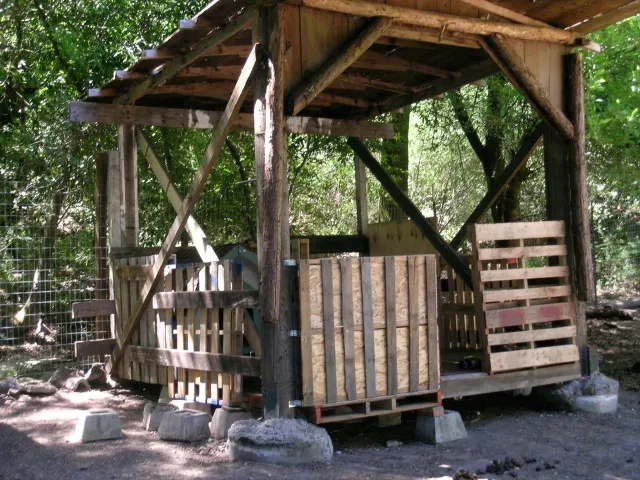 Covered pallet pavilion goat shelter elevated on blocks with wide roof overhang