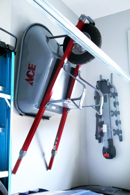 Wheelbarrow and bikes mounted vertically on heavy duty garage hooks