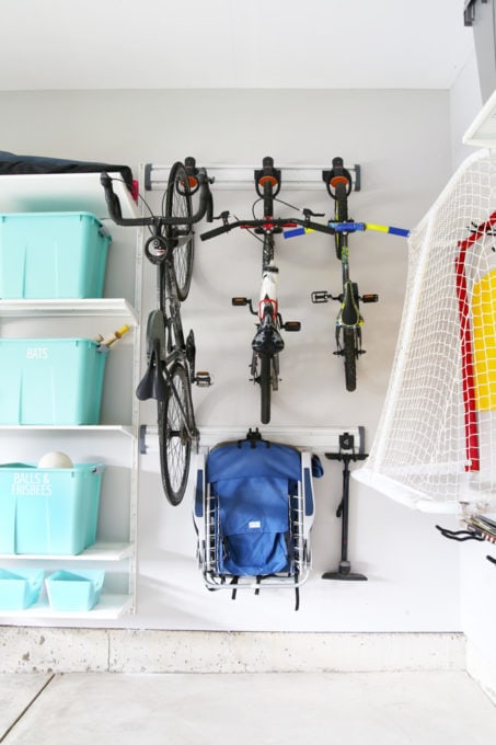 Bike hanging vertically beside wall shelving system