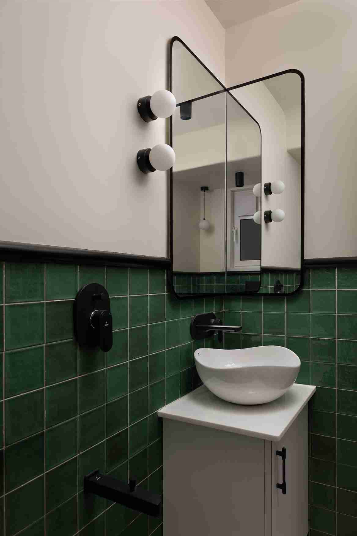 Small bathroom with white square tiles and dark grout, mint green vanity, black faucet, round mirror, and a small plant for a fresh accent.