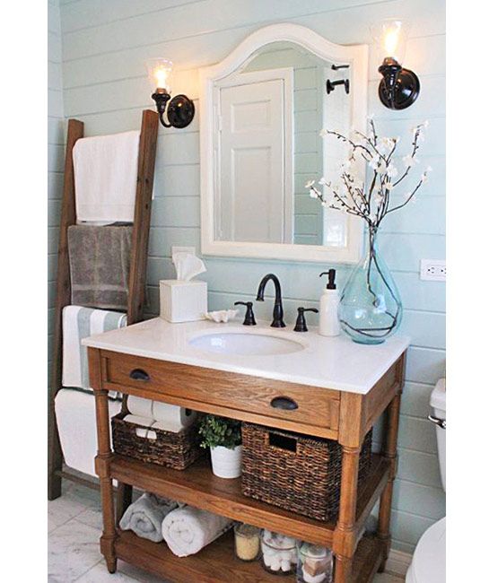 Small bathroom with pedestal stone vanity, warm pendant lighting, backlit mirror, and warm plaster walls creating a cozy glow.