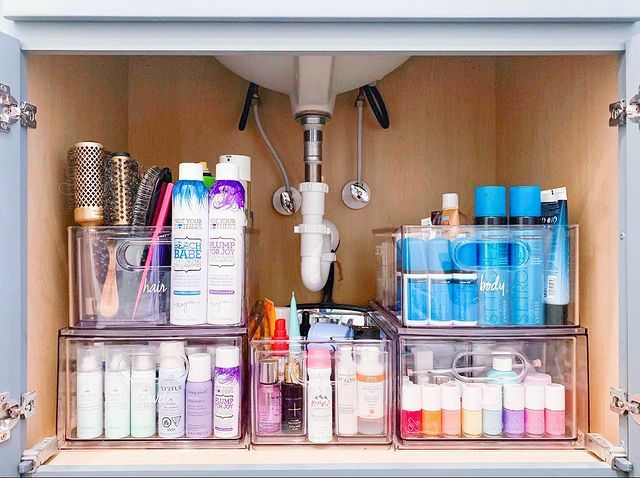 Colorful hair products arranged in clear bins and lazy Susan under sink