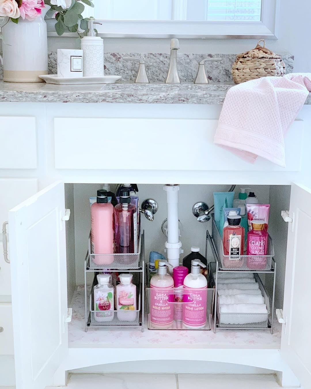 Organized cleaning supplies with glass spray bottles and clear drawers under sink