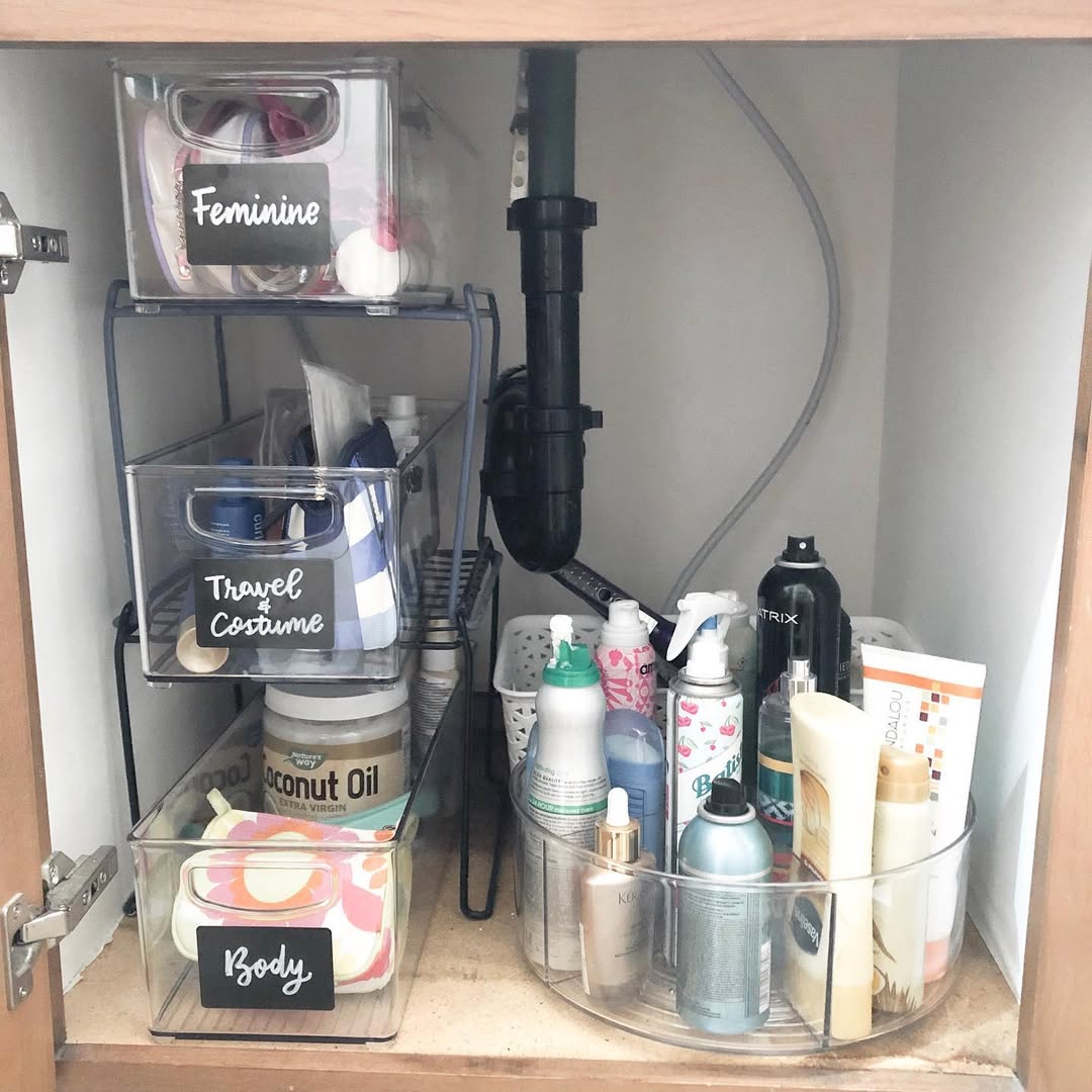 Layered clear bins with rustic wood labels under bathroom sink